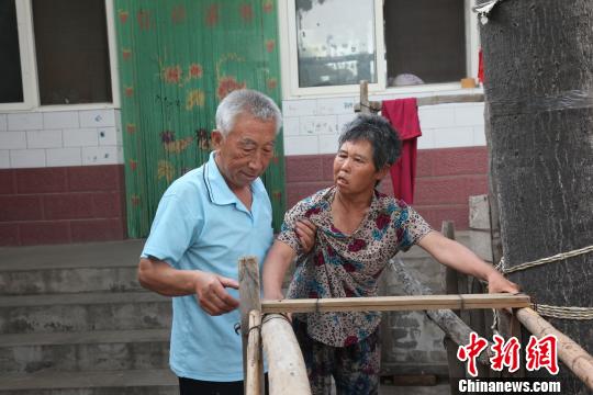 为让妻子慢慢学会走路，李文生每天扶着妻子一遍一遍练习走路。　李院红 摄